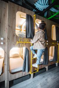 a person on a ladder in a room with bunk beds at Capsule Hostel Logistic Vilnius in Vilnius
