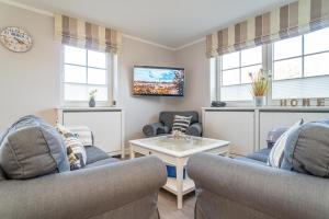 a living room with two couches and a tv at Appartement Meeresleuchten - Nicolinenhof in Wenningstedt