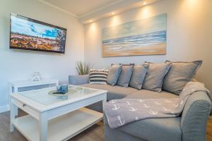 a living room with a couch and a table at Appartement Lachmöwe - Nicolinenhof in Wenningstedt