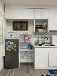 uma cozinha com um frigorífico preto e armários brancos em Venice Raudhah Guest House em Lumut
