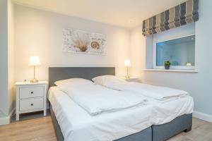a bedroom with two beds with white sheets and two lamps at Appartement Lachmöwe - Nicolinenhof in Wenningstedt