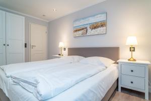 a large white bed in a bedroom with two lamps at Appartement Meeresleuchten - Nicolinenhof in Wenningstedt