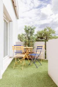 stół i krzesła na balkonie z trawą w obiekcie Aux portes de Bordeaux El Pablo MindUrGuest w mieście Floirac