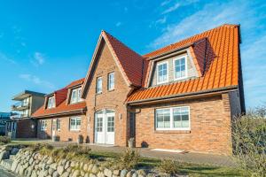 a brick house with an orange roof at Appartement Lachmöwe - Nicolinenhof in Wenningstedt