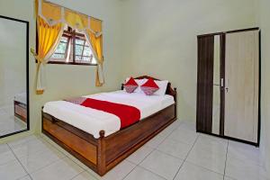 1 dormitorio con 1 cama con almohadas rojas y blancas en OYO 91177 Desa Wisata Duren Sari, en Tasikmadu