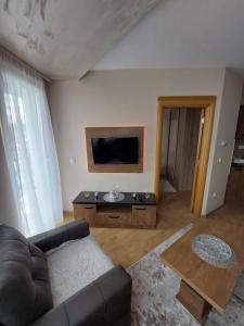 a living room with a couch and a flat screen tv at Golden Apartman in Zlatibor
