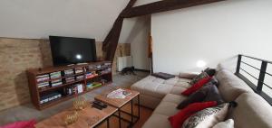 Una sala de estar con un sofá y un televisor de pantalla plana. en Le Clos d'Ô Les Rapiettes maison proche Sarlat avec piscine privée, en Prats-de-Carlux