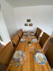 a long wooden table with chairs and plates and glasses at Gelbes Haus Seenland Ferienwohnungen XL in Elsterheide +39 photos