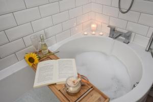 a bath tub with a book and a flower and candles at A spacious home from home with spectacular views in Heywood