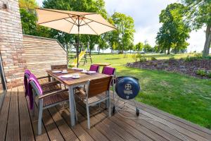 a table and chairs with an umbrella on a deck at Ferien_HAUS AM AHORNECK _ THEA in Göhren-Lebbin +15 photos