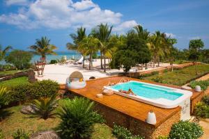 a pool with people sitting in it next to a beach at Fruit & Spice Wellness Resort Zanzibar in Kizimkazi