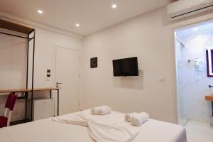 a white bedroom with a bed and a tv on the wall at Vila Shpetimi in Ksamil