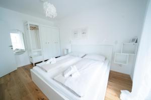 a white bedroom with a white bed with two white towels at Apartment Seekind by Cosy Homes in Reifnitz