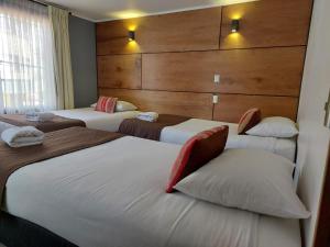 a hotel room with three beds in a room at Hotel Angelmontt in Puerto Montt