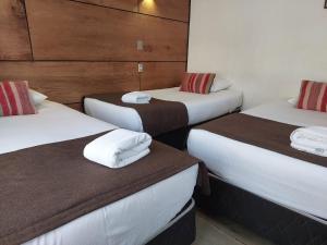 drie bedden in een hotelkamer met handdoeken erop bij Hotel Angelmontt in Puerto Montt