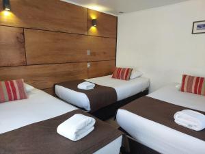 a hotel room with two beds with towels on them at Hotel Angelmontt in Puerto Montt