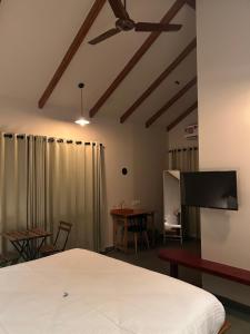 um quarto com uma cama e uma televisão de ecrã plano em SylVan Resort em Wayanad