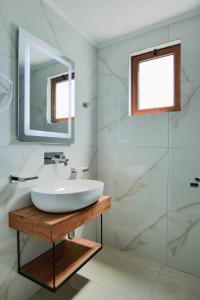 a white bathroom with a sink and a mirror at Vila Shpetimi in Ksamil