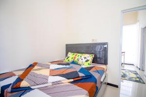 巴图Villa Mulyo E4 by Sans Villa的卧室里有一张床，床上铺着色彩鲜艳的被子