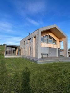 una casa moderna con un prato verde davanti di Magnifique villa nature le Bois d'Aura a Luisans