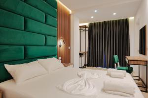 a bedroom with a large white bed with a green headboard at Vila Shpetimi in Ksamil