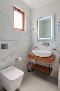 a white bathroom with a sink and a toilet at Vila Shpetimi in Ksamil