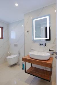 a white bathroom with a sink and a mirror at Vila Shpetimi in Ksamil