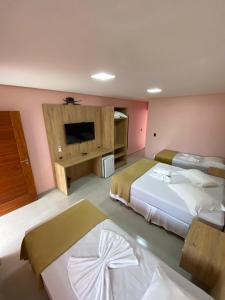 a hotel room with two beds and a flat screen tv at Pousada Baía dos Açores in Penha
