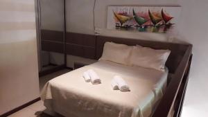 Una cama con dos zapatillas encima. en La Piazzetta Apt 10, en Pipa