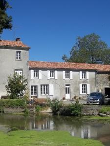 um grande edifício branco ao lado de uma massa de água em la chambre du moulin de la bleure em Moncoutant