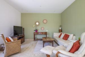 Una sala de estar con un sofá blanco y un televisor. en Maison des Fleurs, en Vedène