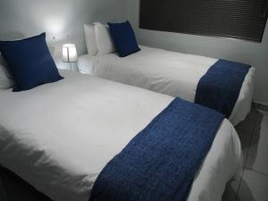 two beds in a hotel room with blue pillows at LEKKER RUS in Bloemfontein