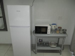 a white refrigerator next to a table with a microwave at LEKKER RUS in Bloemfontein