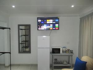 a television on the wall of a kitchen with a refrigerator at LEKKER RUS in Bloemfontein