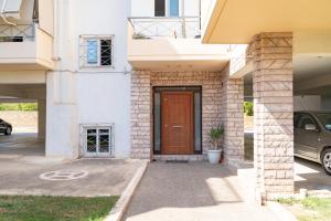 uma porta da frente de uma casa com um carro em Koropi 3 bedroom Luxurious Apartment 5 pers- Angel House em Koropíon