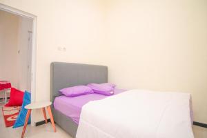 una camera da letto con un letto con cuscini viola e uno sgabello di Villa Riesky A11 by Sans Villa a Batu