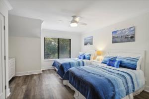 2 camas en un dormitorio blanco con sábanas azules en Sea You Soon, en Hilton Head Island