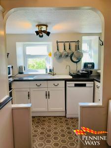 a kitchen with white cabinets and a sink at Harthopeburn Cottage, St Johns Chapel in Saint Johns Chapel