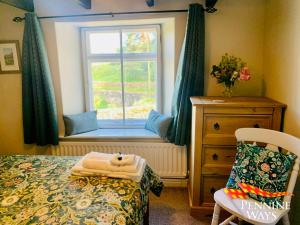 a bedroom with a window with a bed and a chair at Harthopeburn Cottage, St Johns Chapel in Saint Johns Chapel