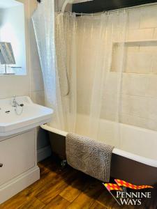 een badkamer met een bad, een wastafel en een douche bij Harthopeburn Cottage, St Johns Chapel in Saint Johns Chapel