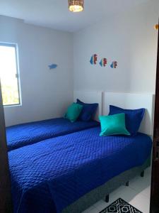 a bedroom with a blue bed with blue pillows at Aconchego do francês - Praia do Francês - Alagoas/Maceio in Marechal Deodoro