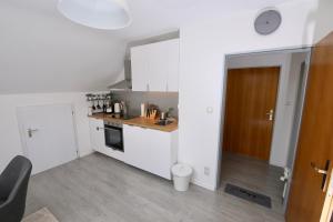 a small kitchen with white cabinets and a wooden door at NATURBLICK Apartments: Moderne Ferienwohnung in Grebenhain