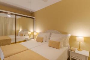 a hotel room with two beds and a mirror at Tranquil Beachside Stay - Atlantic Gardens Beach in Funchal