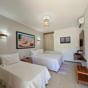 um quarto de hotel com duas camas e uma televisão em Pousada Coqueiro Beach em Luís Correia
