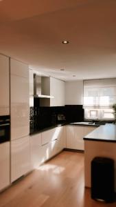 a kitchen with white cabinets and a black counter top at Dune Du Clémot in Blankenberge +21 photos