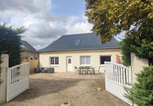 a house with a white fence and a patio at Maison de campagne in Sceaux-dʼanjou
