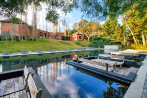 una piscina con panchine e una casa sullo sfondo di Be House & Spa by Oceana Suites a Punta del Este