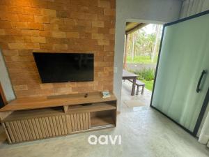 uma sala de estar com televisão numa parede de tijolos em Qavi - Excelente casa com piscina privativa #Lambari06 em São Miguel dos Milagres