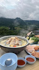 einen Tisch mit einer Pfanne an Lebensmitteln und Teller mit Lebensmitteln in der Unterkunft ภูลังกาซีวิว in Ban Sakoen