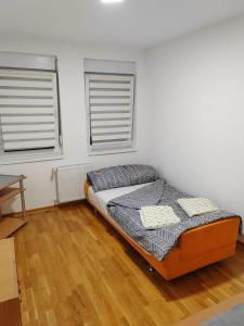 a bed sitting in a room with two windows at Apartman SM in Sremska Mitrovica